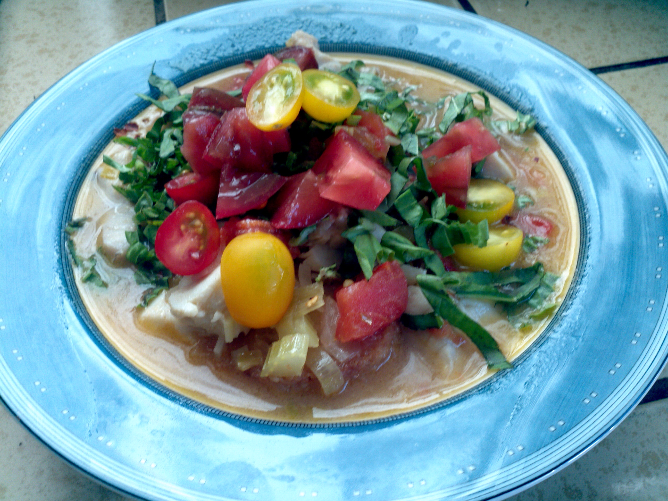 Soup topped with fresh basil and tomatoes